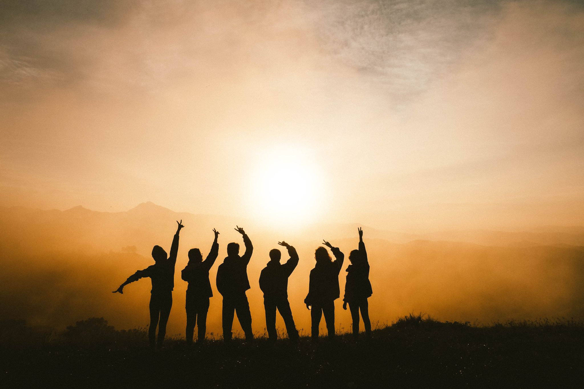 Group silhouette celebrating at sunset